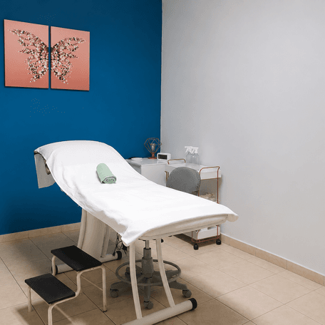 Sala de atendimento da Attualita com parede azul e maca preparada para avaliacao
